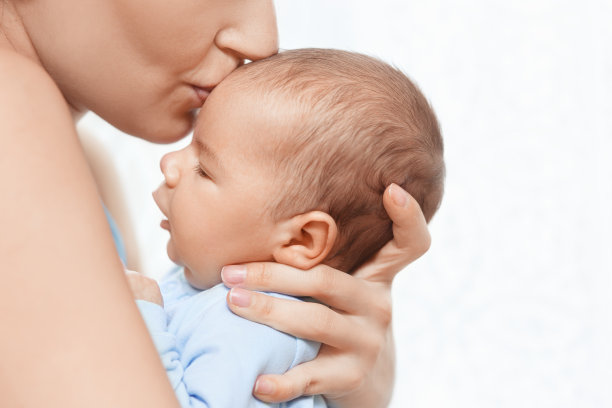母亲抱着并亲吻新生的婴儿图片下载
