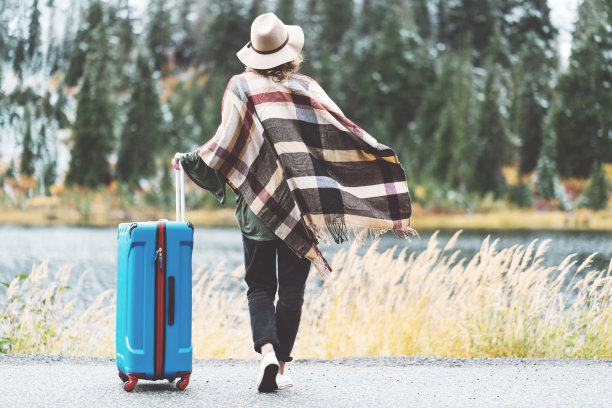 带着亮蓝色行李箱的旅行女人在看山的荒野图片下载