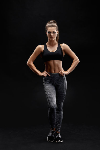 一个强壮的女人在运动服装肌肉腹部的照片。健身女性模特在黑色背景下摆姿势图片下载