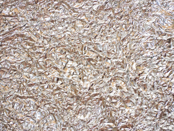 米色皱巴巴的箔闪闪发光。金属箔质地的肤色。节日的背景图片下载