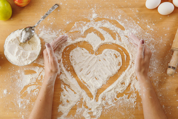 在厨房的桌子和其他配料上用面粉手绘心形。前视图。图片下载