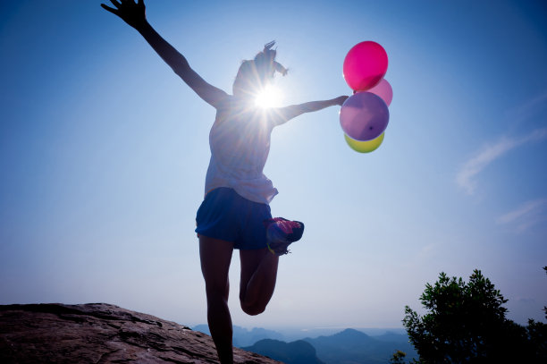 快乐的女人在日出的山巅边跑着气球图片下载