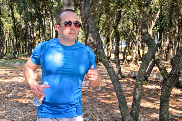 英俊的年轻人跑越野跑在夏季森林的小径。年轻的男性运动员在大自然中训练和锻炼。慢跑健身理念。休闲运动。图片下载