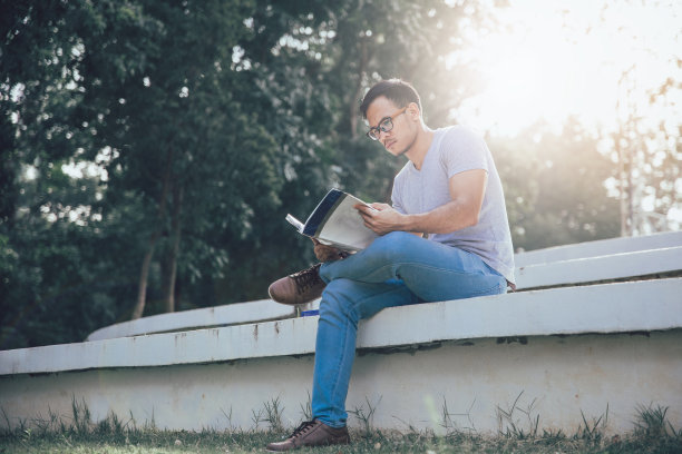 年轻的亚洲学生在公园里看书图片下载