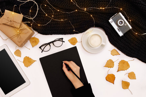 女人的手在一件黑色针织毛衣里，拿着笔靠近空白的纸，从上面看图片下载