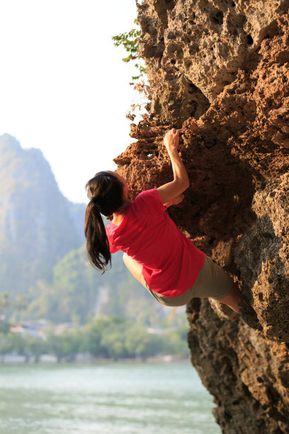 一位年轻的攀岩者正在海边的悬崖上攀岩素材图片