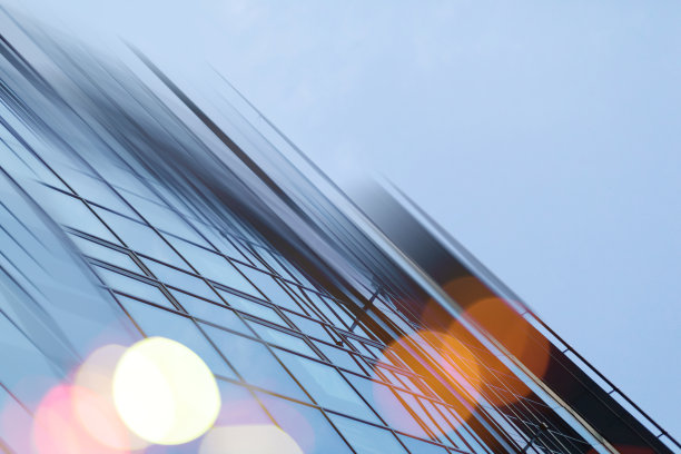 摘要商业现代城市城市未来建筑背景。房地产概念，动态模糊，高层摩天楼立面的玻璃反射，色调蓝色的画面与散景图片下载