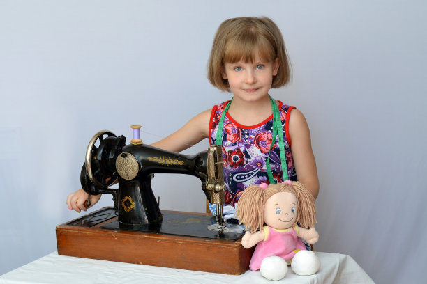 孩子，孩子，(小女孩)女裁缝在旧缝纫机上为洋娃娃缝制衣服图片下载