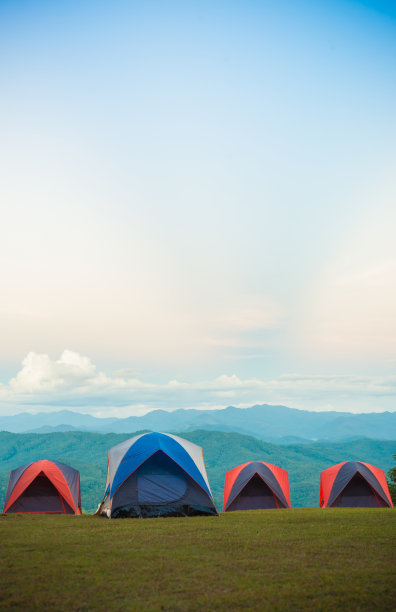 四个露营帐篷设置在草地上与美丽的青山背景图片下载