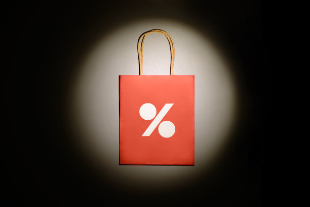 红色购物袋与百分之标志在光线的景点灯光在黑暗的背景。图片下载