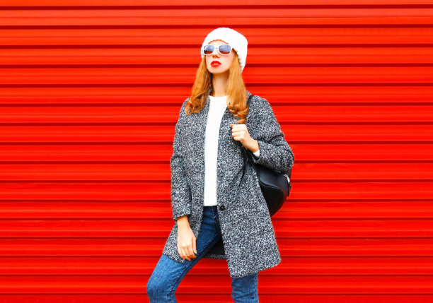 时尚漂亮的年轻女子在红色背景上装摆姿势图片下载