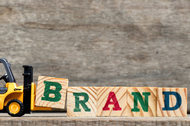 黄色塑料叉车在木质背景上保持字母B来完成单词品牌图片下载