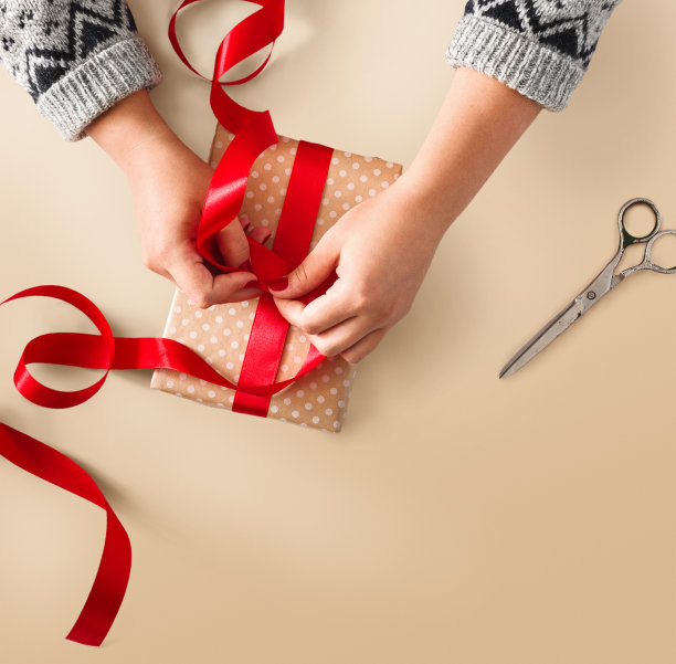 女人的手用红丝带包裹圣诞礼物图片下载