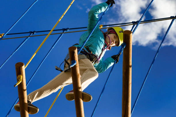 一个戴着黄色头盔的女孩在冒险公园里玩。图片下载