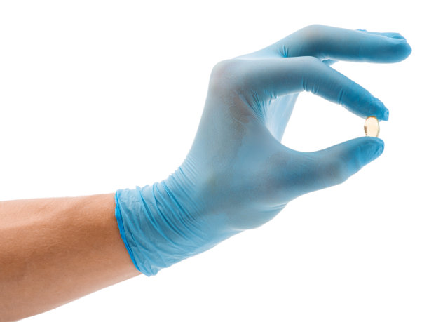 一只蓝色手套里有一个鱼油胶囊，孤立在白色的背景上图片下载