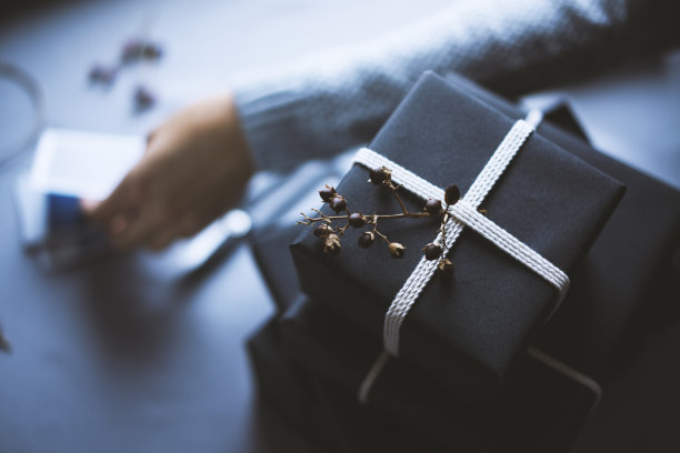 女人穿着灰色的毛衣，礼物包裹在桌上用灰色的桌布素材图片