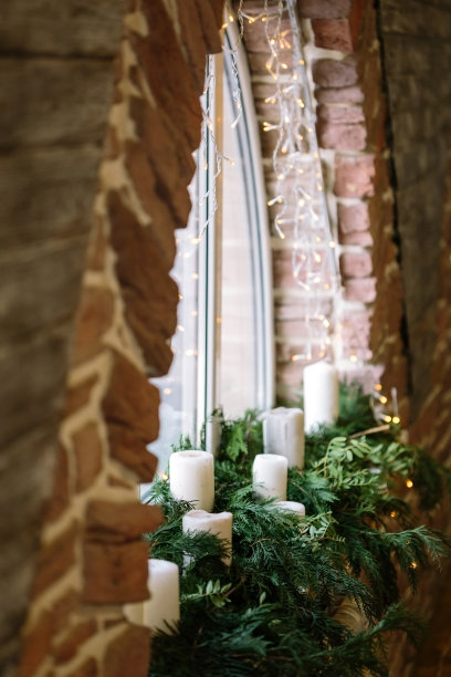 室内、冬季、假日概念。墙上的红砖围成半圆形的窗户，新鲜毛茸茸的云杉树枝和窗台上未点亮的蜡烛图片下载