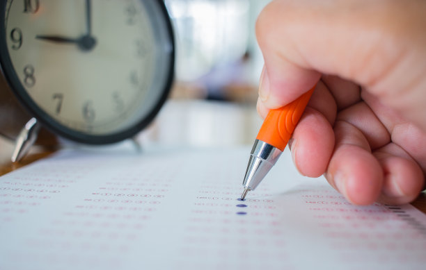 亚洲学生采取光学形式的标准化考试近闹钟与手握黄笔为期末考试在中学，大学教室，教育理念图片下载
