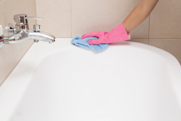 员工将橡胶防护手套用抹布清洗并擦拭浴缸。女佣或家庭主妇关心房子。春季一般或定期清理。商业清洁公司理念。图片下载