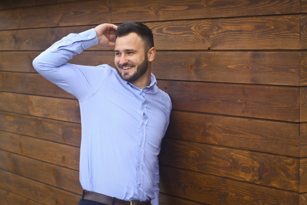 一个英俊男子的肖像在一个木制的墙壁背景衬衫。商人，穿着时髦的老板。设计素材照片图片下载