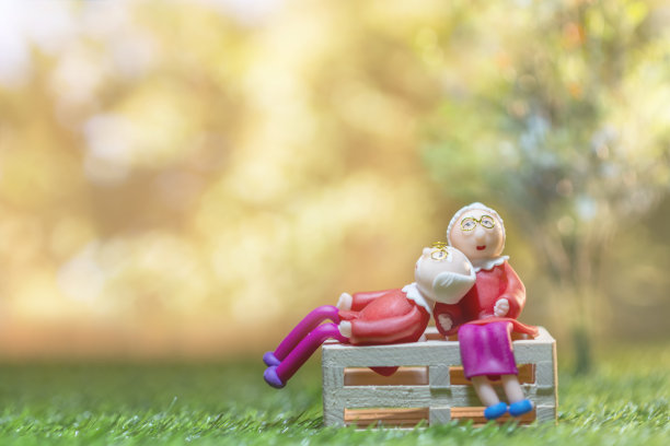 老娃娃老两口坐在绿草地上省钱出售。投资和家庭观念。图片下载