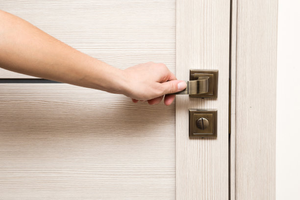 女人的手打开木门。素材图片