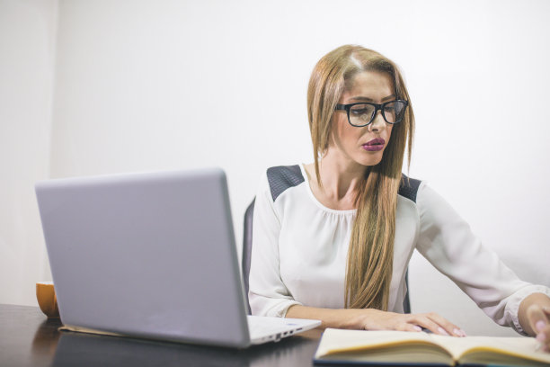 一个愉快的长发女人坐在办公室电脑前的肖像图片下载