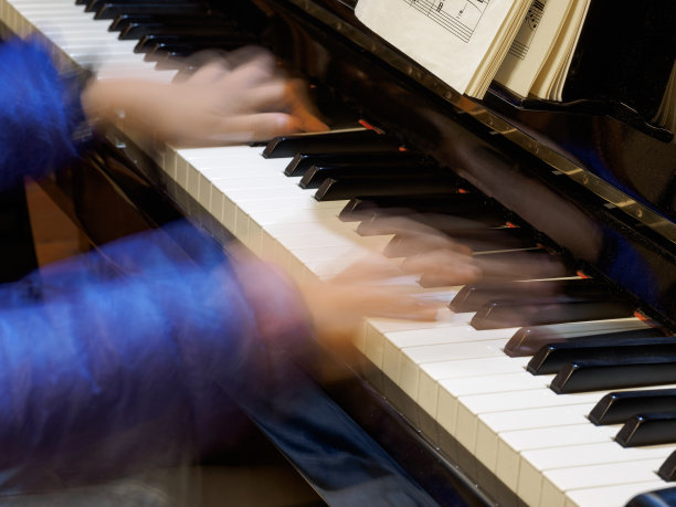 在钢琴键盘上舞动的手指。图片下载