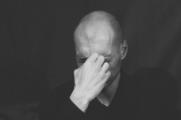 身穿黑衬衫的年轻男子独自坐着，感到情绪压抑和焦虑（黑白照片）素材图片