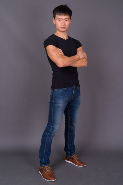 年轻的中国男子穿着黑色衬衫，映衬着灰色的背景图片下载