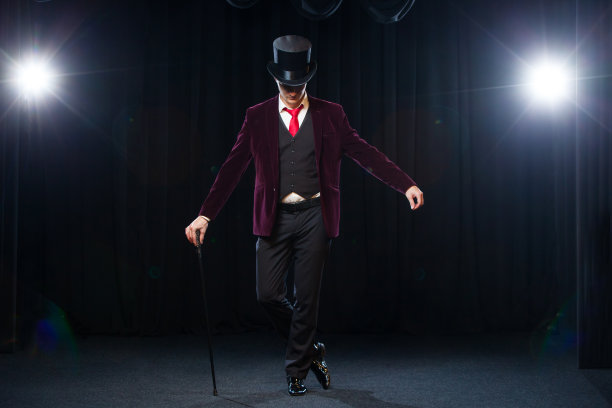 魔术师，变戏法的人，有趣的人，黑魔法，幻觉站在舞台上一根美丽的光手杖图片下载