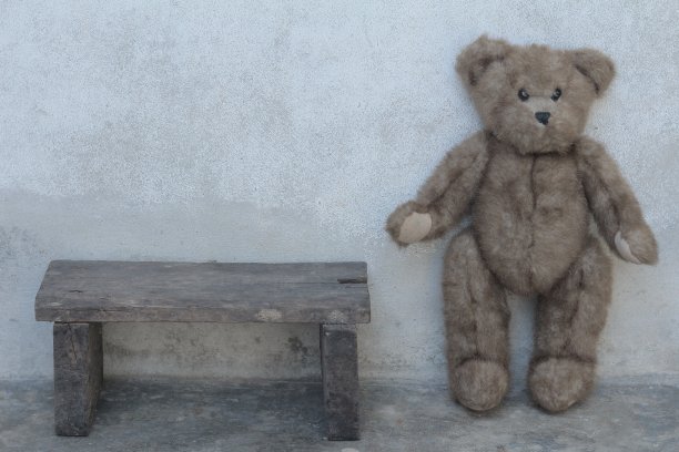 泰迪熊独自站在经典的木椅旁图片下载