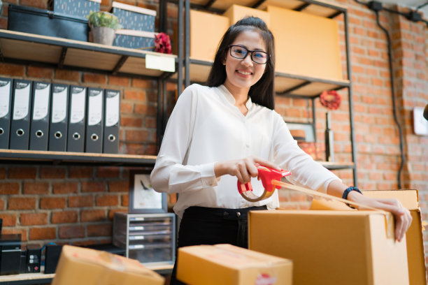 女商人正在打包箱子寄给客户。素材图片