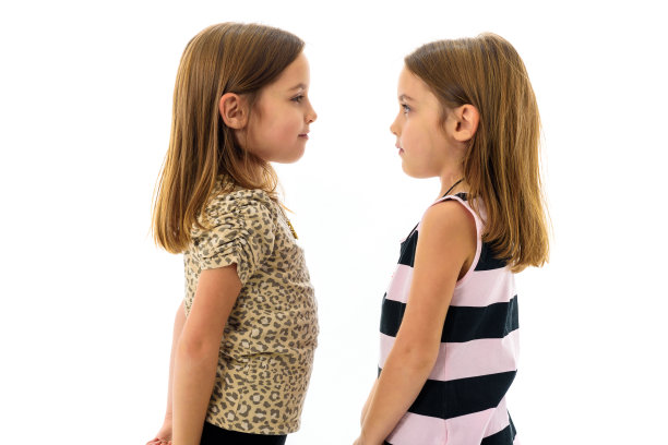 一对同卵双胞胎女孩微笑着看着对方。图片下载