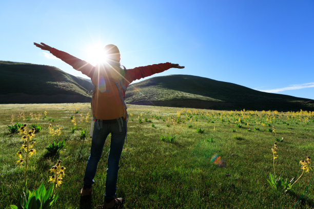 快乐的女徒步者在日出的山上举起双臂图片下载