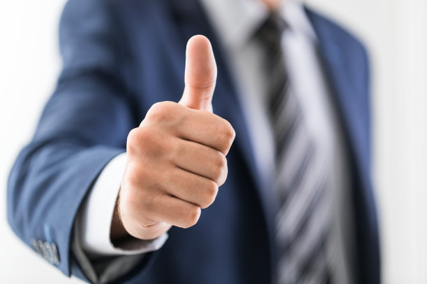 商人竖起大拇指做手势。素材图片