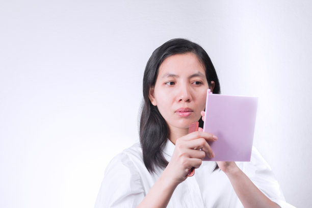 肖像美丽的泰国女人看着镜子，同时美化他的脸与文字空间。图片下载