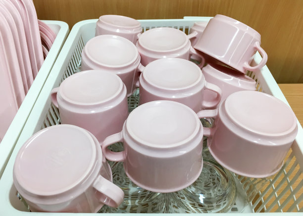 粉红色的杯子和玻璃杯放在塑料篮子里。图片下载