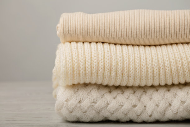 白色和米色的针织衣服(毛衣、围巾、套头衫)。图片下载