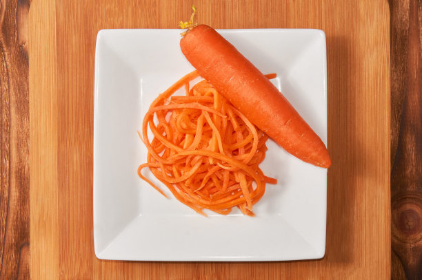 把磨碎的胡萝卜放在一个白色的杯子里，放在木制的背景上。食品的背景。图片下载