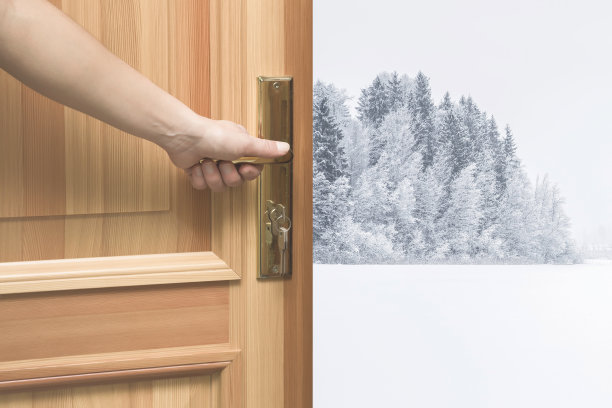 受欢迎的冬季。女人的手在家里打开木门与白雪覆盖的小径和树木。冬日的概念。图片下载