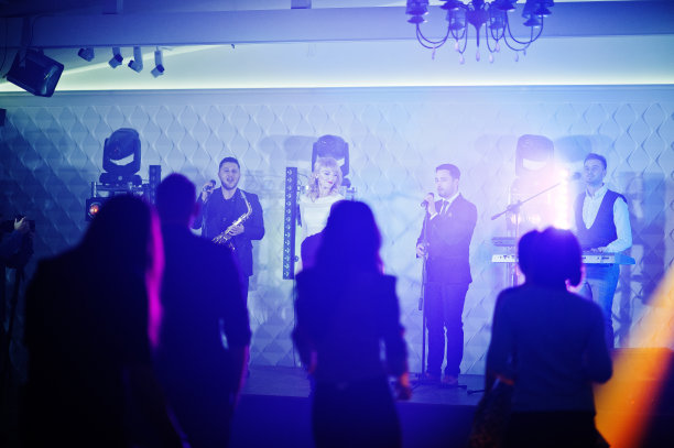 音乐现场乐队在舞台上与不同的灯光和人群歌迷一起表演。素材图片