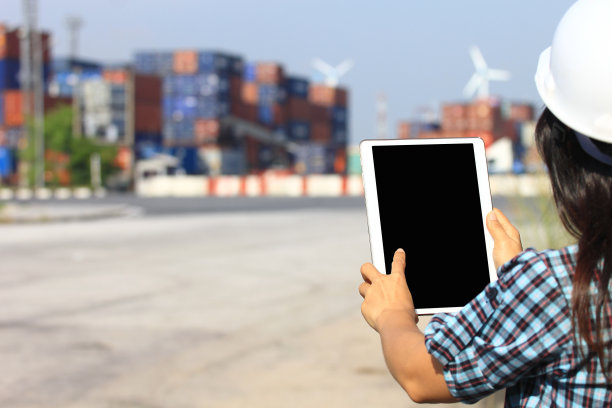 工程师手持数字平板与空白屏幕前集装箱和进出口背景，技术和商务运输的国际物流概念图片下载