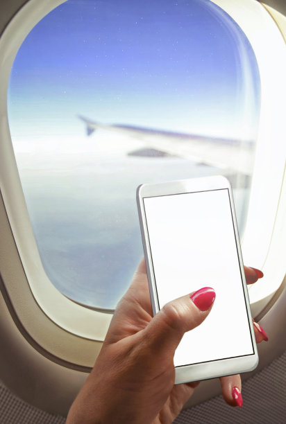 一名女子坐在靠近窗户的地方，手里拿着智能手机在车上工作图片下载