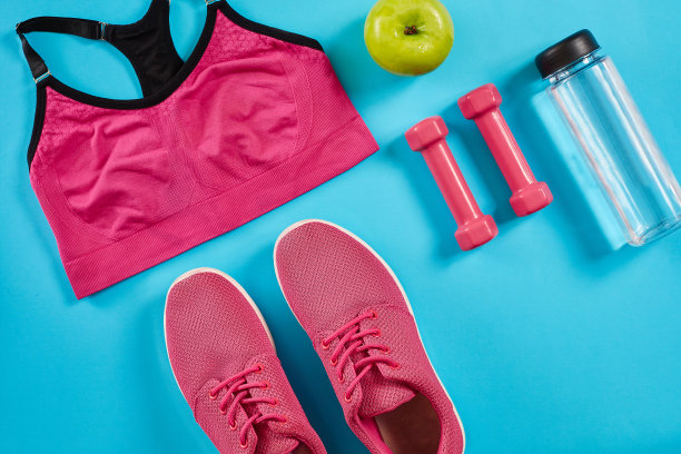 运动员套装，女性服装，哑铃和水瓶在亮蓝色的背景图片下载