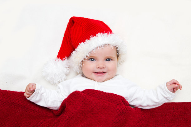 照片中的婴儿戴着圣诞老人帽，裹着白毯子图片下载
