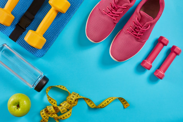 运动员套装，女性服装，哑铃和水瓶在亮蓝色的背景图片下载