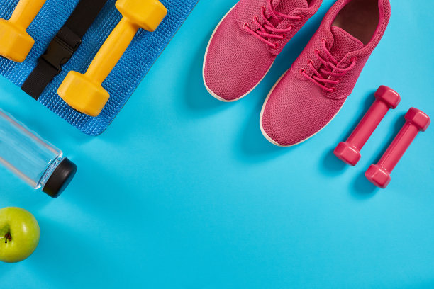 运动员套装，女性服装，哑铃和水瓶在亮蓝色的背景图片下载