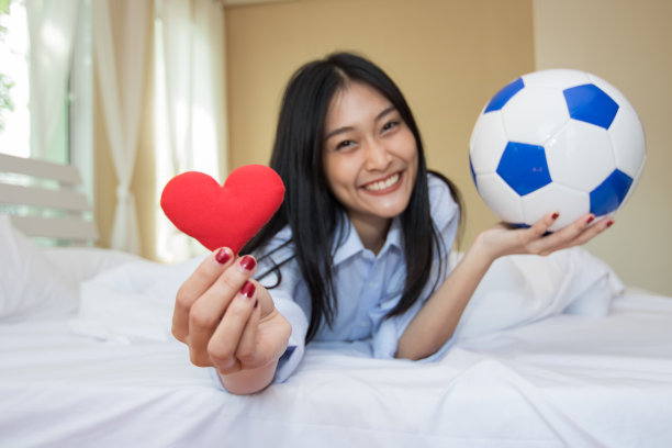 一个女人在卧室里玩足球。图片下载