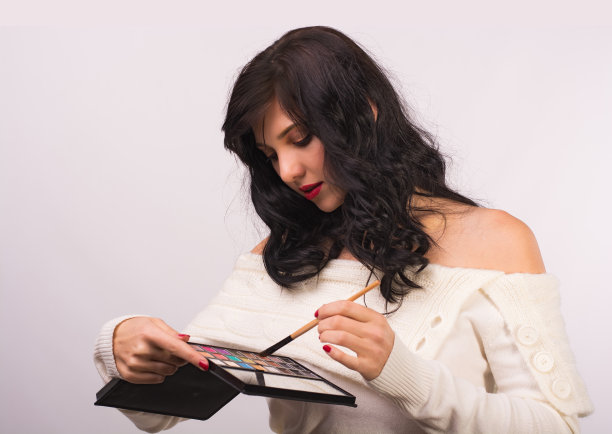 年轻美丽的女子用梳子和一套化妆品。图片下载